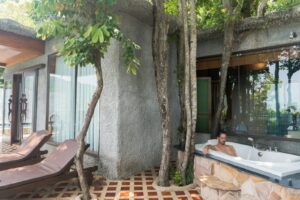 A man sitting in a bathtub next to a tree